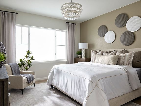 A cozy and well-designed bedroom with a large bed, plush bedding, and a decorative chandelier overhe