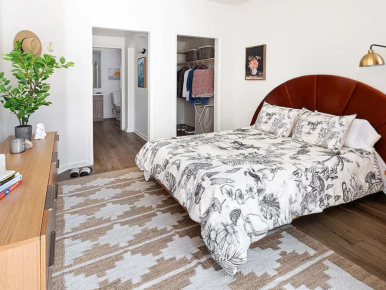 Spacious apartment bedroom with large closet and wood-style flooring.
