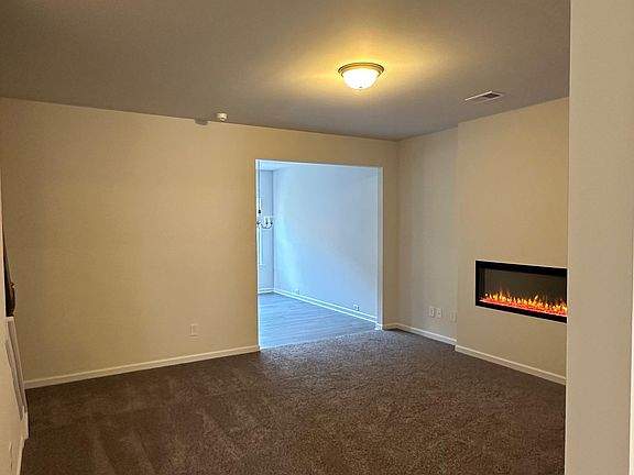 Spacious living room with plush carpeting and a built-in electric fireplace for added warmth and style.