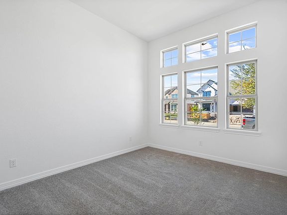 A welcoming second bedroom with large windows and comfortable plush flooring.