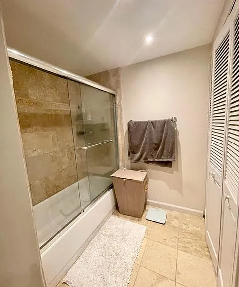 Bathroom with sliding door shower/tub. Full size, Whirlpool washer dryer set in sliding doors on the right. Shelving for storage as well.