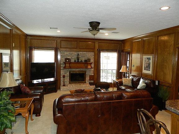 The family room is large and has rich block paneling, brick wood-burning fireplace with convenience of gas logs and pool views. There is an exit door to the patio in the far right corner.
