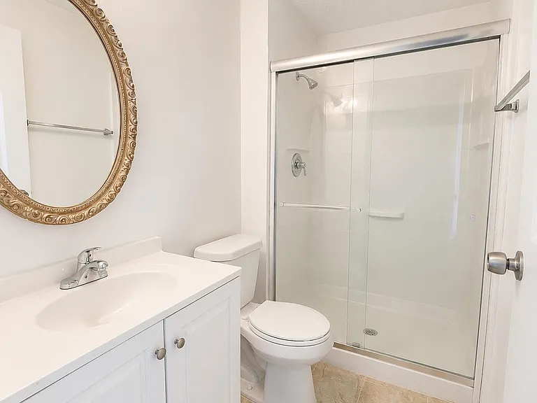 Clean full bath with single-sink vanity, framed mirror, and tub/shower combo with sliding glass doors.