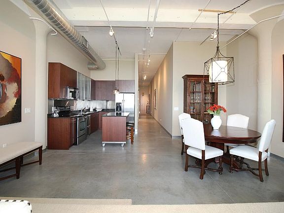 View of Foyer, dining room, kitchen showing the cement floors, original pillars, exposed ceilings