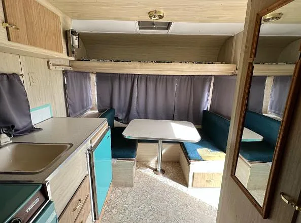 Compact kitchenette and dinette with built-in booth seating, table, sink, and storage cabinets for everyday meals.