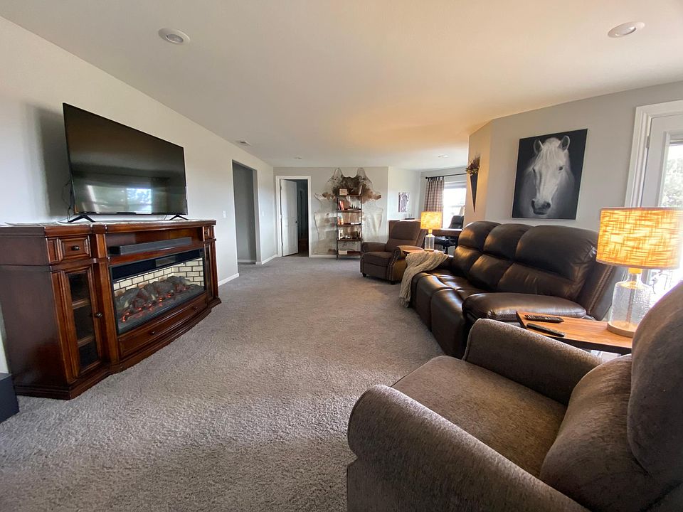 Living room with electric fireplace, high ceilings, leather reclining couch.