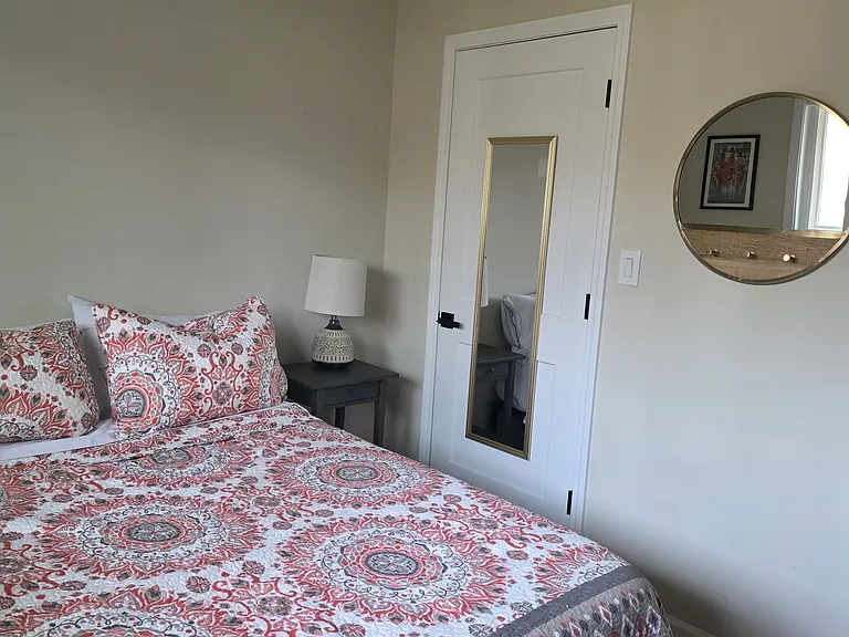 View of full bed, nightstand, bedroom closet, and mirrors