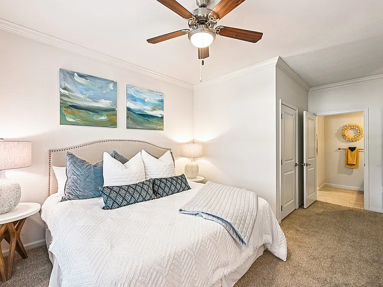 Inviting bedroom with plush bedding, abstract art, and warm lighting creates a cozy and serene atmosphere.