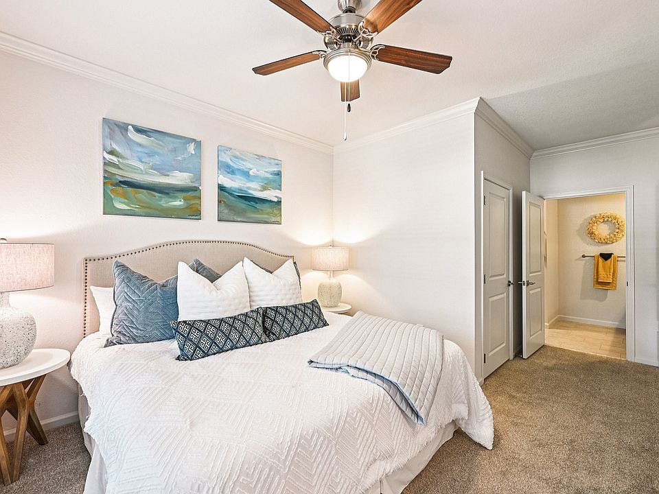 Inviting bedroom with plush bedding, abstract art, and warm lighting creates a cozy and serene atmosphere.