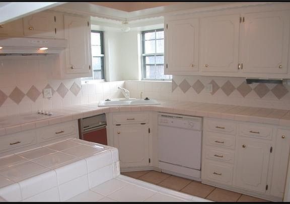 KITCHEN WITH TILE COUNTERS & BACKSPLASH, WHITE CABINETS, BUILT IN OVEN AND ELECTRIC COOKTOP. ALSO HA