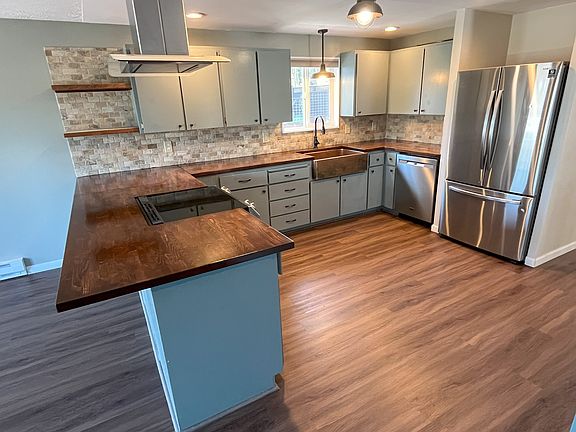 Large and open kitchen with stainless appliances, copper sink, and butcherblock counters
