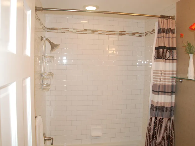 Full bath, bright subway tile with elegant accents and coordinated decorations and amenities.