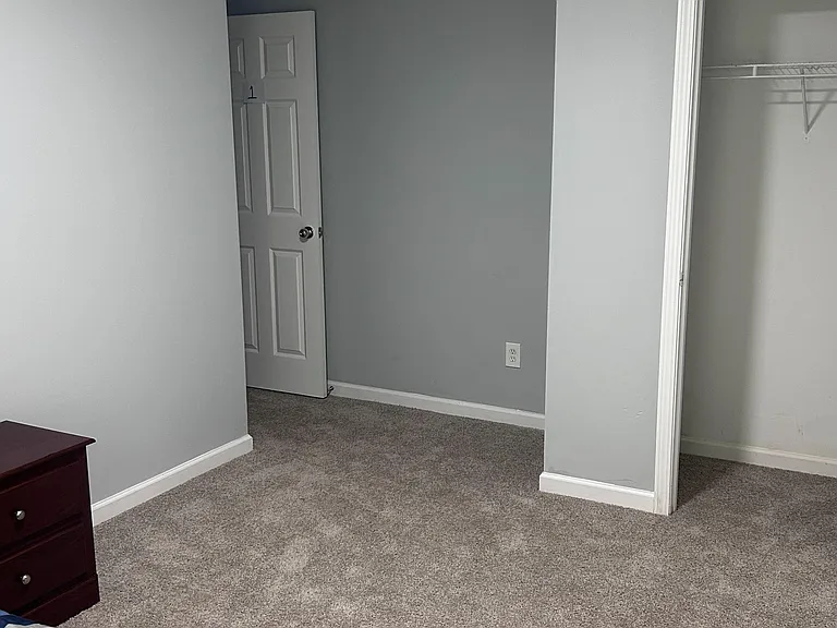 Carpeted bedroom with neutral walls and a reach-in closet, offering space for a full bed and dresser.