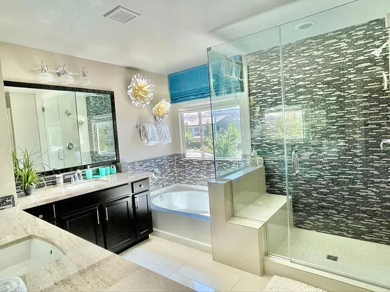 Master bath. L shaped counter. Two sinks/mirros. Bathrub and walk in shower with bench.