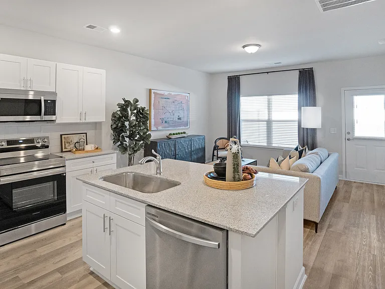 Spacious kitchen with an island, ample storage, stainless steel appliances and view into the living room.