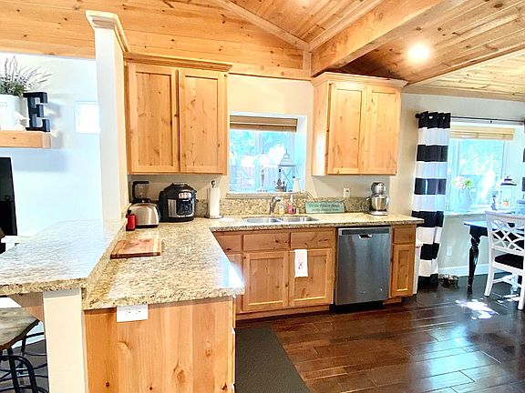 View of kitchen with granite countertops, beautiful cabinets and flooring, stainless steel appliances, gas cooktop, large dining area off kitchen.