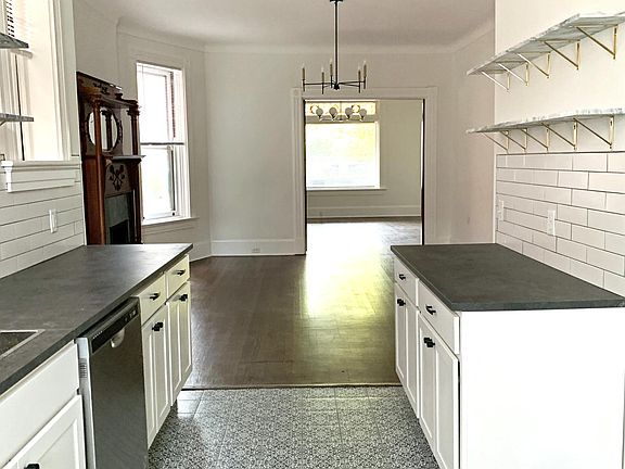 Galley kitchen with beautiful patterned floor tile, marble floating wall shelves, and new appliances. 
*Refrigerator and range have now been installed*