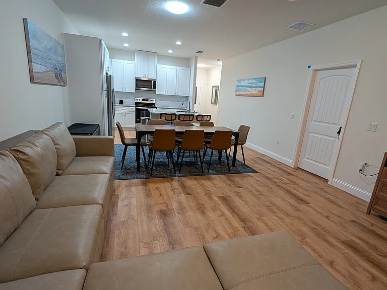 Open-concept living area with master bedroom off living room; foyer leads to garage and corridor with smaller bedrooms and hall bath.