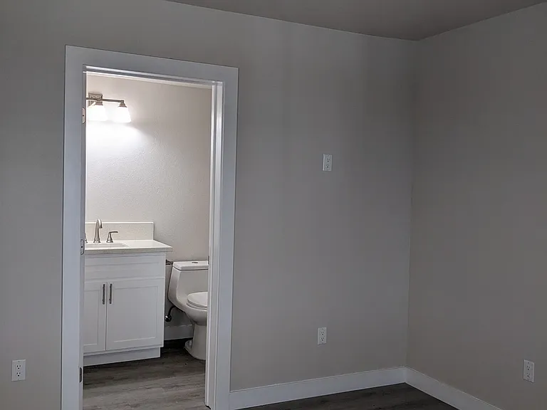 Bedroom with private bathroom and ceiling fan at The Hardison Apartments in Pasadena, California.