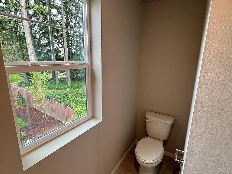 Full bathroom, view from bath/shower toward the window and toilet section.