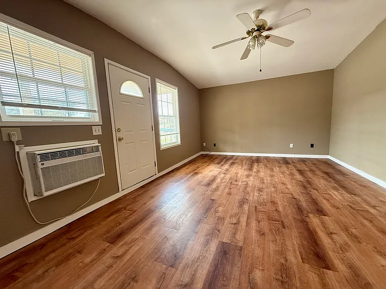2 nice windows with blinds and living room with fan.