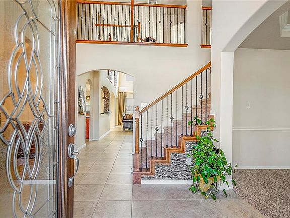 GRAND ENTRANCE: An open floor plan, formal to the left, office to the right, wrought iron staircase, and high ceilings.