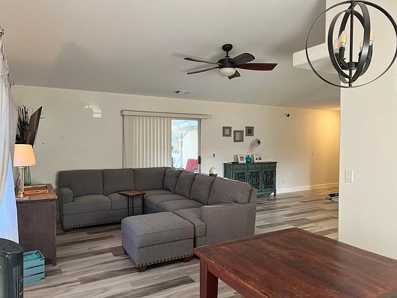 Living space with vaulted ceiling and ceiling fan. Slider door to backyard with awning