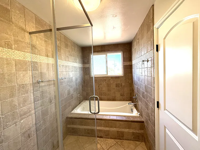Primary bath with tub and separate shower. Bathroom is all in travertine stone.