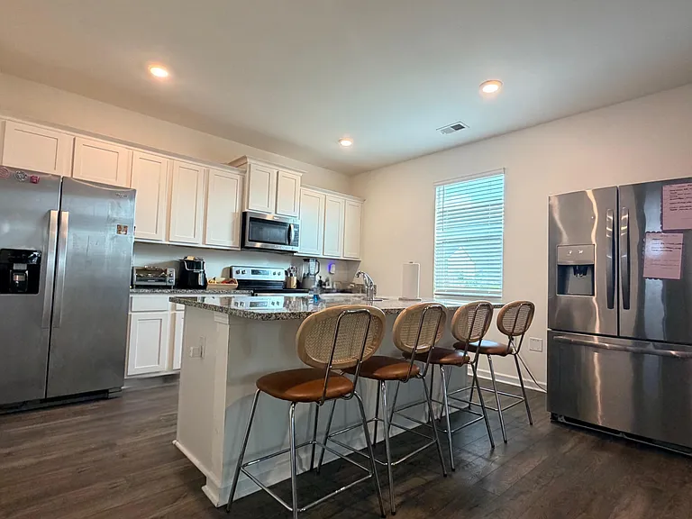 Open kitchen with white cabinetry, granite peninsula seating for four, and stainless steel appliances for easy meal prep.