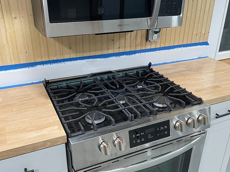 Gas range and microwave with beautiful tongue and groove custom wood backsplash