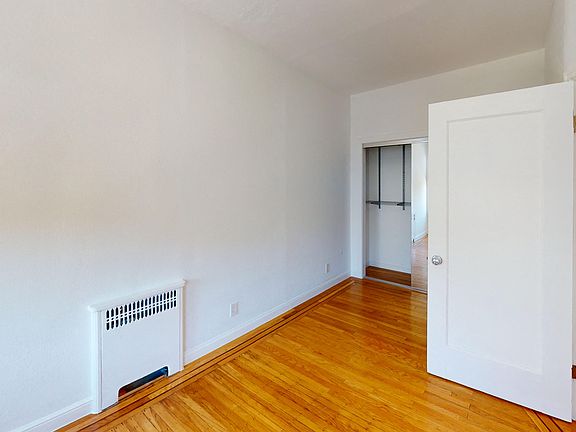 Bright bedroom with wood-like floor and a closet with mirror