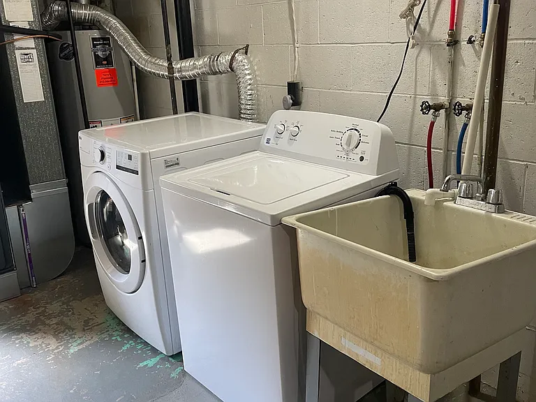 Basement with clothes washer, clothes dryer, and stationary tub.