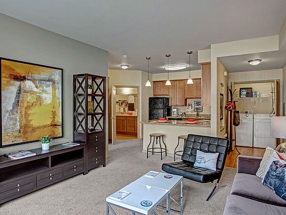 A spacious living room with a view into the kitchen over the bar