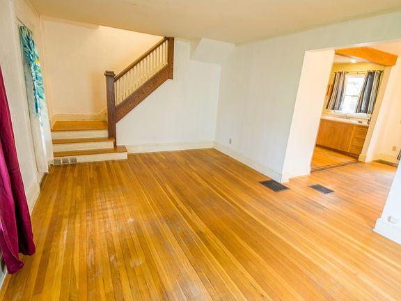 Living room with staircase leading to second floor. Archway leads to dining room.