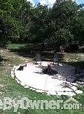 Property behind house. : This concrete fire circle is located outside fenced in pool/deck/yard. Fire