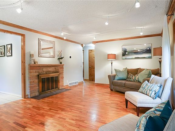 Formal living and dining rooms are open to one another, thus visually expanding the space! Vintage stone wood-burning fireplace with glass doors and track lighting.