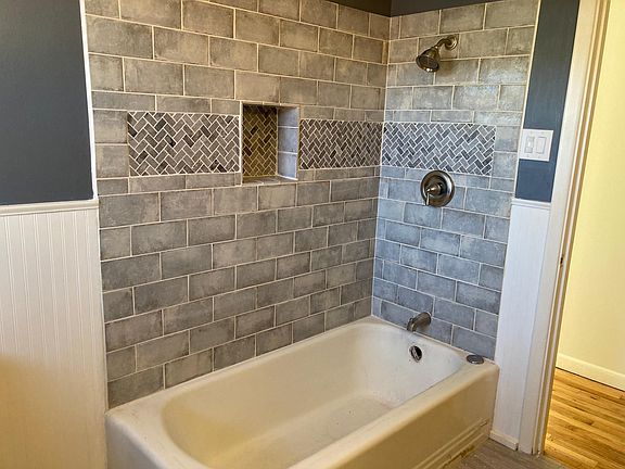 New custom herringbone tile accents and niche for shampoo.