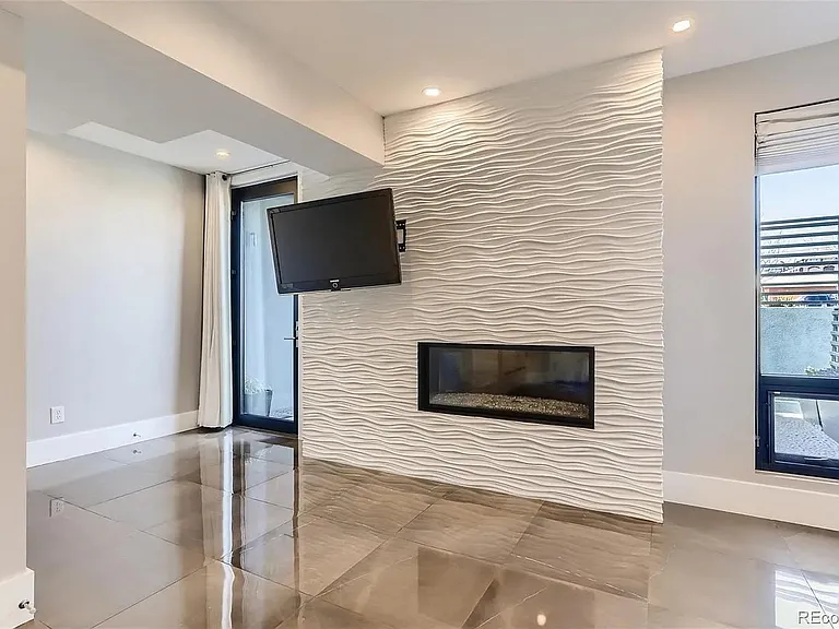 garden level bedroom on frontside of home with windows, fireplace, mounted TV and oversized patio