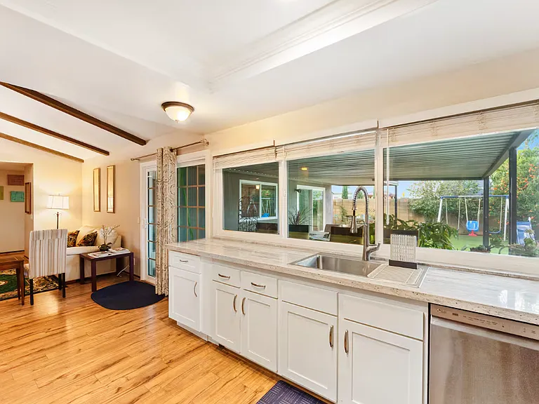 This kitchen has that sliding door that leads to the covered patio and all green (fruit trees and flowers) backyard. This kitchen has natural light because of the 3 big windows and the view of the backyard .