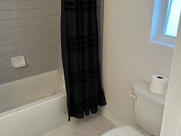 New toilet with tile floor having the appearance of marble.