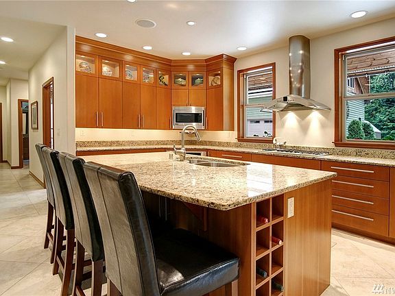 Kitchen features custom cabinets with upper glass display cabinets, GE monogram appliance package including warming drawer, microwave and five-burner gas range, granite counters, and large walk-in pantry!