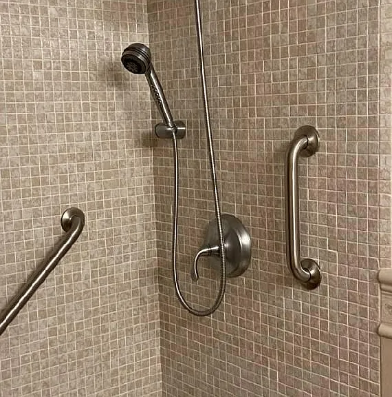 Kohler fixed and hand shower heads, long diagonal and short vertical grab bars.