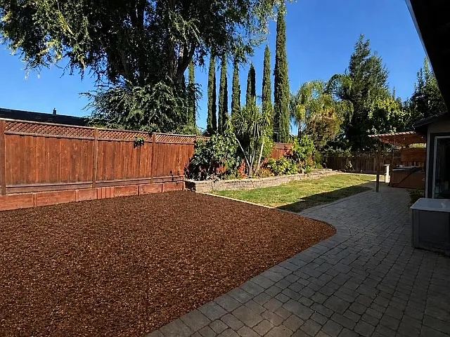 Backyard, pergola, firepit area with built in bench, grass area room for swing set in tan bark. Shaded most of the day