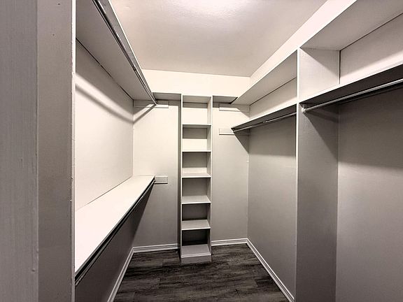 Spacious walk-in closet with double hanging rods and built-in shelving for organized storage.