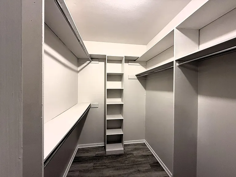Spacious walk-in closet with double hanging rods and built-in shelving for organized storage.