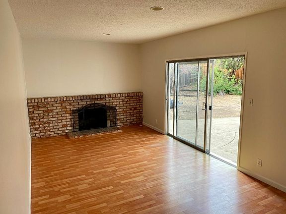 Freshly painted family room with working fireplace and sliding doors to backyard. This room has hardwood laminate flooring. The rest of the house is hardwood floor.