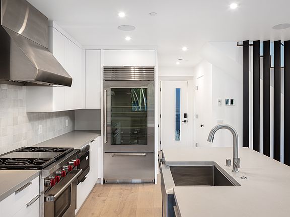 Touchless sink faucet and deep stainless steel sink. Fully featured dishwasher, Wolf range hood and undercounter lighting.