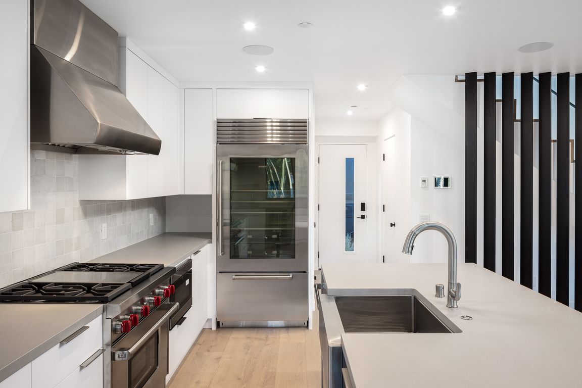 Touchless sink faucet and deep stainless steel sink. Fully featured dishwasher, Wolf range hood and undercounter lighting.
