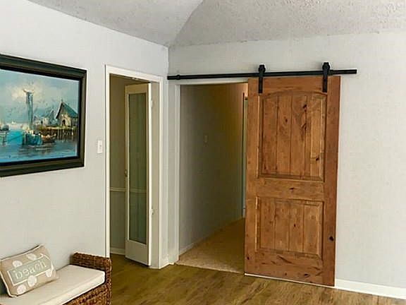 Large family room with fireplace, beautiful laminate flooring, barn door