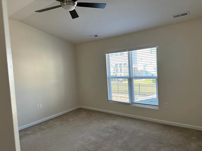 A view from within the main bathroom facing out into the main bedroom, where you can see the fan and the vaulted ceiling.
